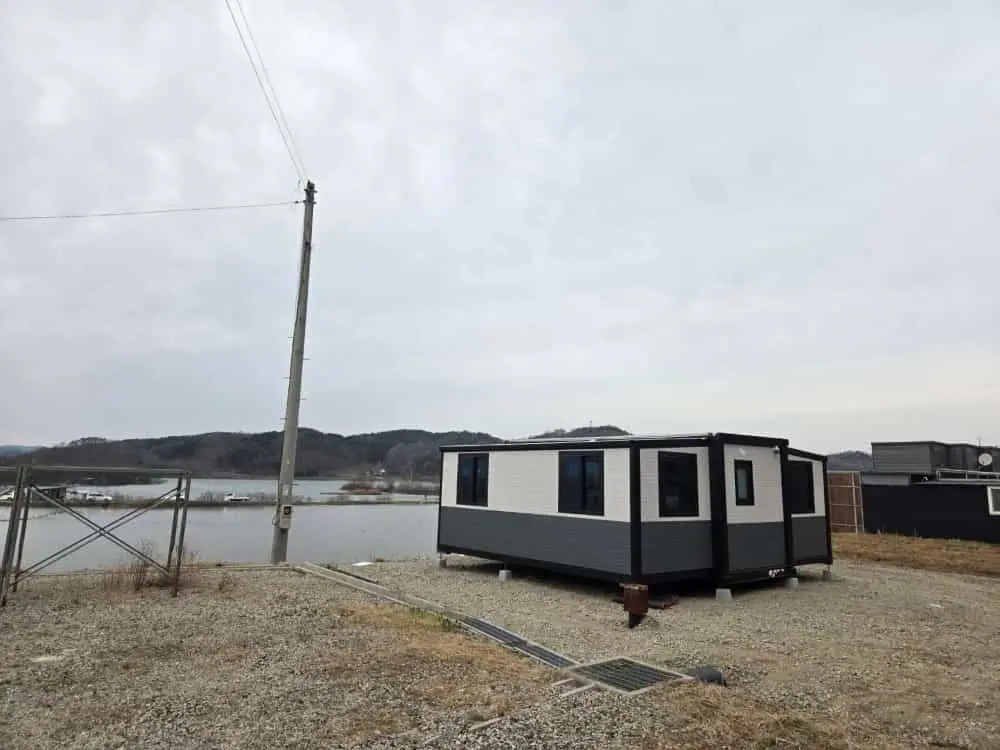 Projeto de casa contêiner expansível de 20 pés: um refúgio moderno à beira de um lago na Coreia do Sul.