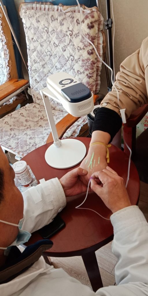 Buscador de venas portátil en uso, que ayuda a los profesionales médicos a localizar venas para la inserción intravenosa.